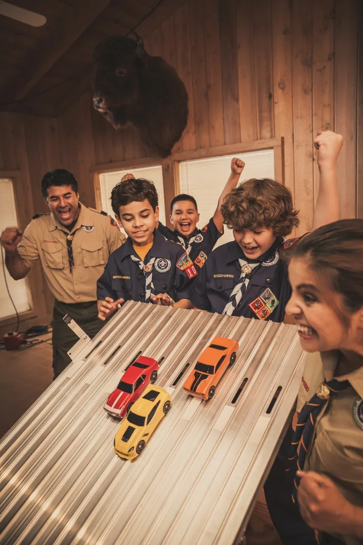 Cub Scouts excitedly watching cars race on a Pinewood Derby track