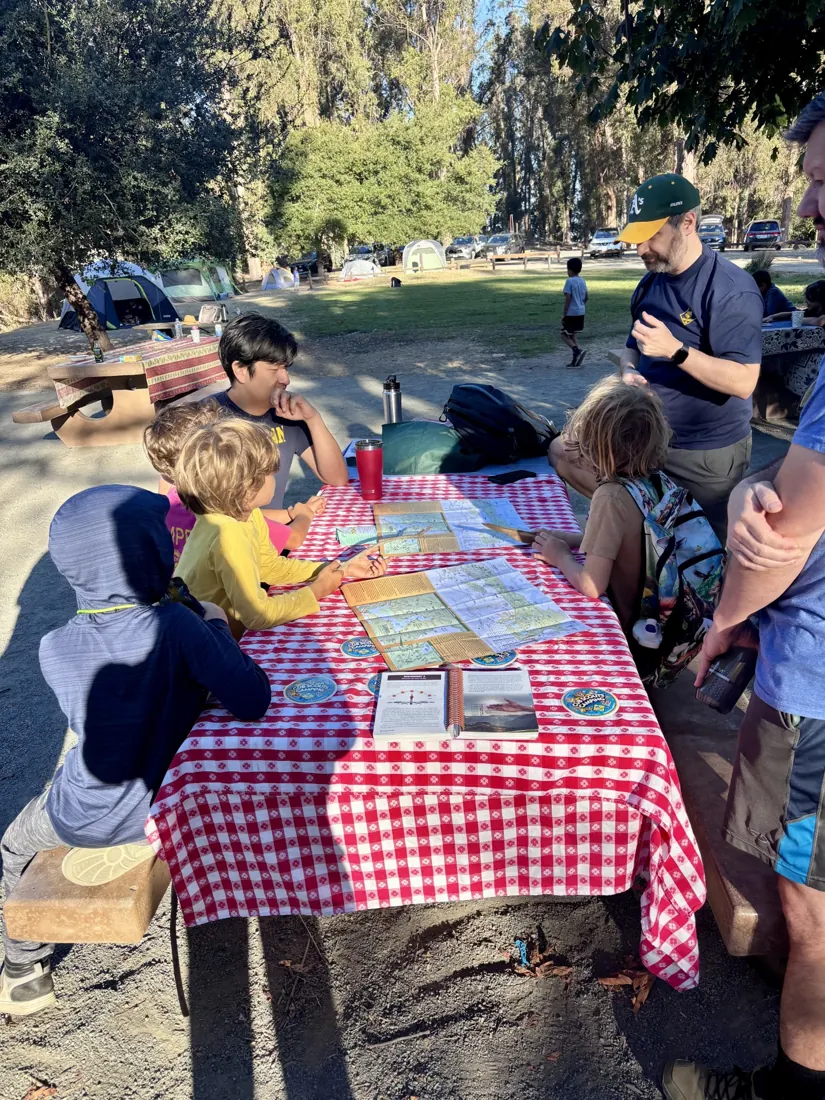 Pack 212 Scouts working together with maps at a picnic table during a campout