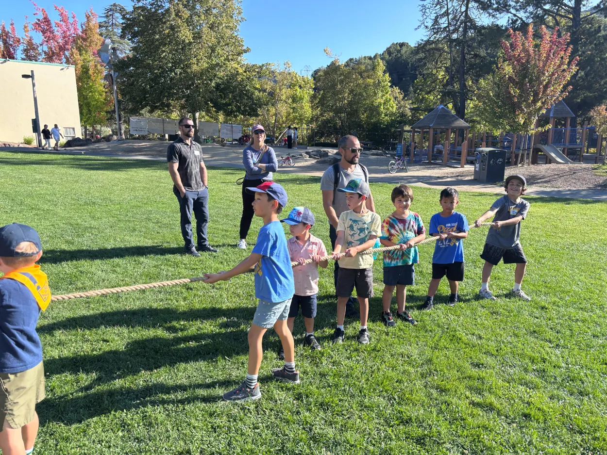 Pack 212 children working together in a friendly outdoor tug-of-war